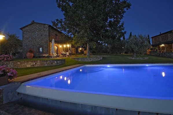 Guests can enjoy a serene pool area surrounded by lush greenery and a charming stone building.