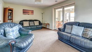 A living room with two leather sofas, a bookshelf, and a painting on the wall. - 1 Bed in Northam, Bideford (oc-cedars) (Northam)