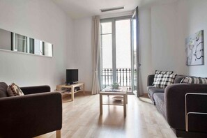A modern living room with a sofa, a coffee table, and a TV on a stand.
