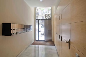A hallway with lockers, a door leading outside, and a tiled floor.