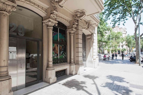 A building facade with classical architectural elements, including ornate columns and a large arched window with metal bars.