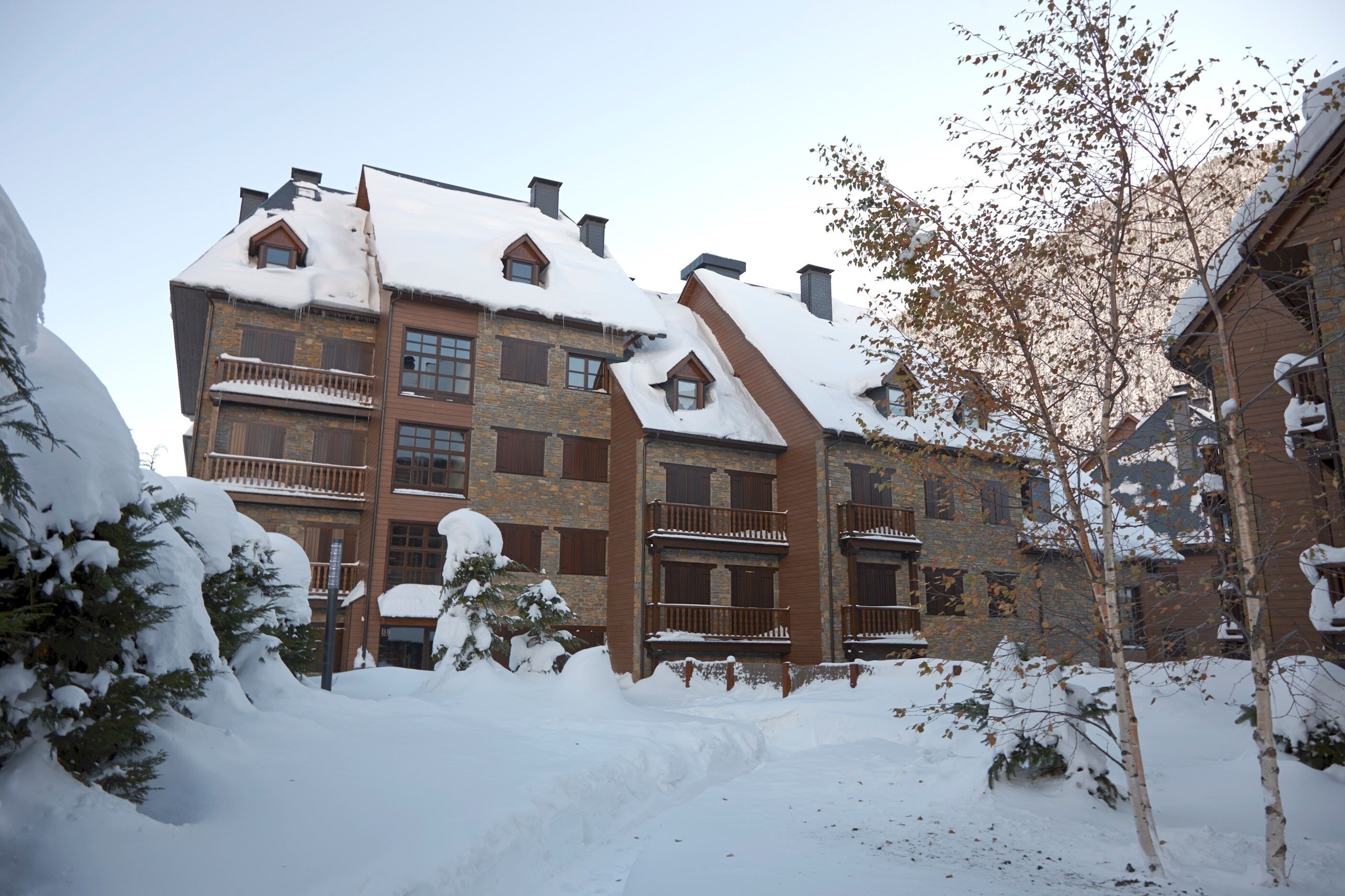 A multi-story building with a snow-covered roof and balconies.