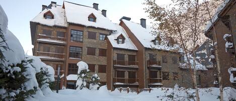 A multi-story building with a snow-covered roof and balconies.