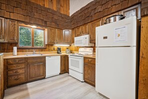 Une cuisine avec des meubles en bois, un réfrigérateur blanc, un four à micro-ondes, une cuisinière et un lave-vaisselle.