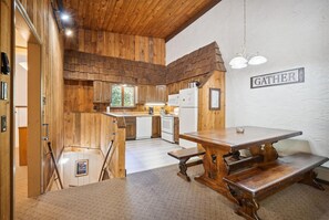 Une cuisine rustique aux murs en bois, avec une cheminée en pierre et un coin repas équipé de bancs.
