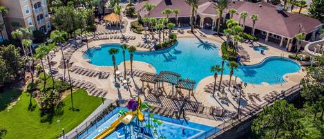 An aerial view of a resort with multiple swimming pools, a water park, and surrounding greenery.