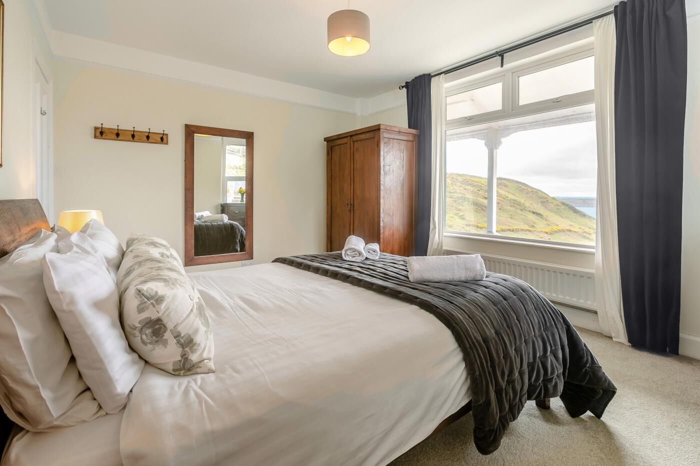 Un dormitorio con cama, espejo, armario y ventana con vistas.
