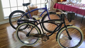 Deux vélos dans une pièce dont le sol est recouvert de planches de bois et qui possède une grande fenêtre.