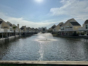 Waterfront property with gabled roofs and balconies, featuring a central water feature and wooden dock.