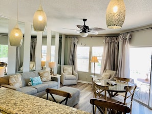Relax in a spacious living area with a plush sofa set, dining table, and ceiling fan.