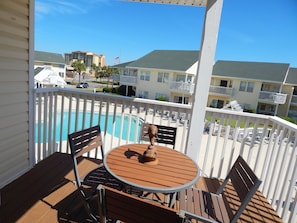 Enjoy a refreshing view of the pool from this balcony with a table and chairs.