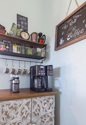 A coffee station with a coffee maker, cups, and a menu sign.