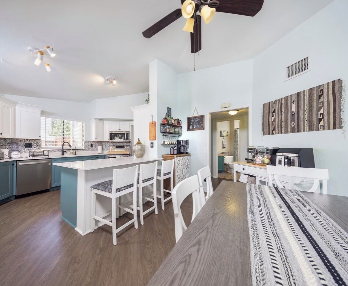 A modern kitchen with a central island, bar stools, and a dining area with a patterned rug.