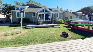 Una casa de dos pisos con un balcón, mobiliario exterior y kayaks.