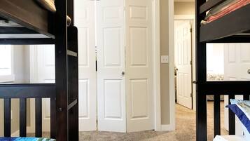 A room with bunk beds, a white door, and carpeted flooring.