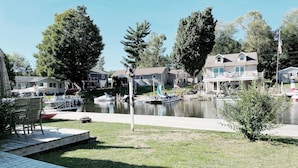 Zona residencial junto al lago con barcos amarrados, una terraza de madera y casas con balcones.