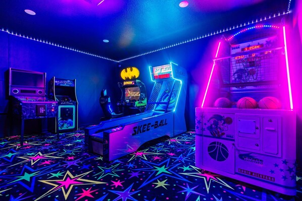 Una habitación con juegos de arcade, incluyendo un juego de Batman y una máquina de Skee-Ball.