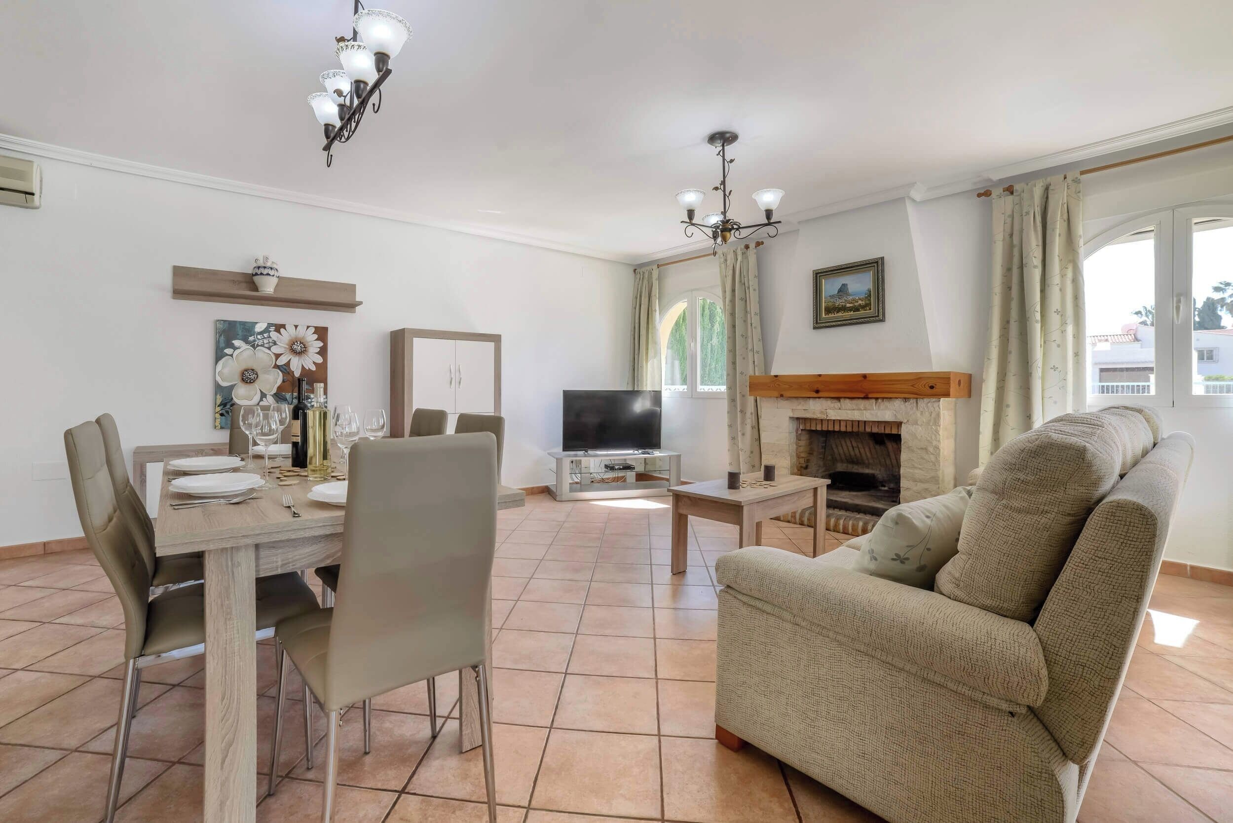 A living room with a fireplace, a dining area with a table set for four, and a television.
