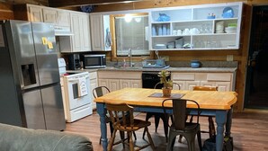Een knusse keuken met houten kastjes, een eettafel en een bank.