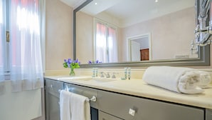 Ein modernes Badezimmer mit einem großen Spiegel, einem Waschbecken mit zwei Wasserhähnen und einem Handtuchhalter.
