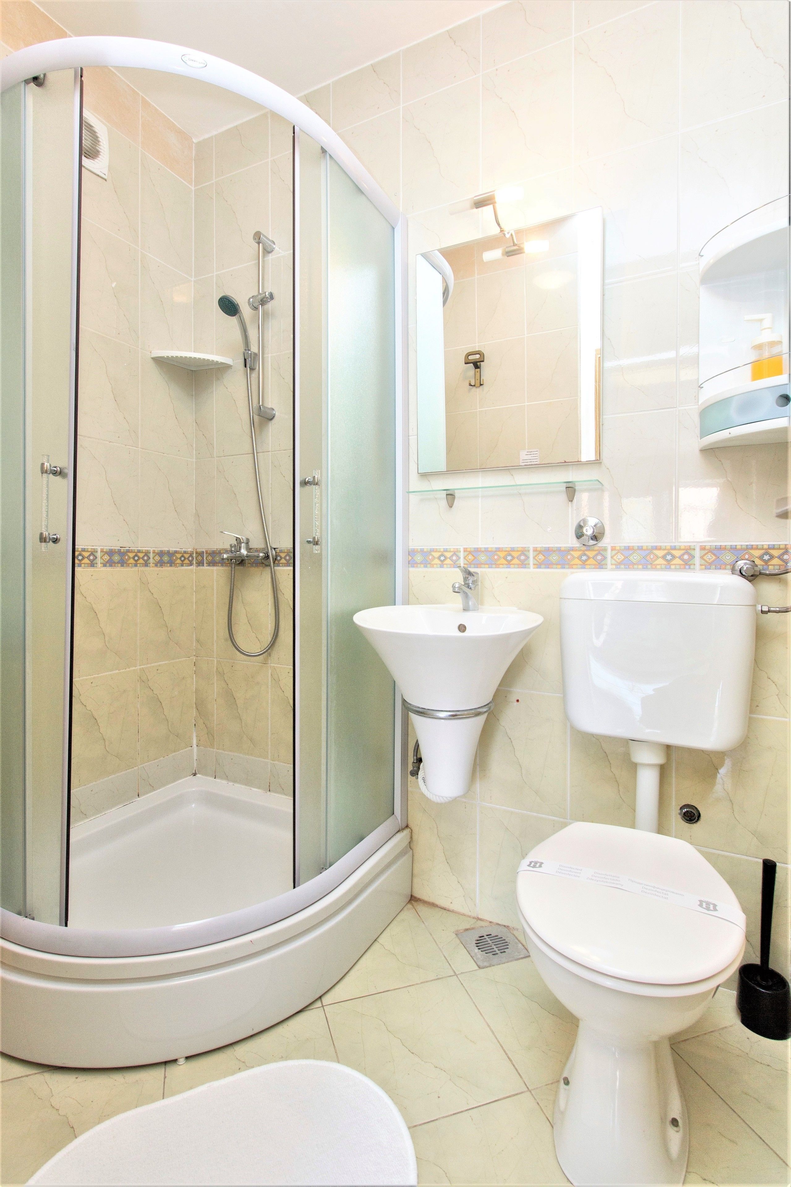 Un baño con ducha de vidrio, lavamanos, inodoro y espejo.