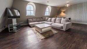 A modern living room with a sectional sofa, a glass coffee table, and a flat-screen TV.
