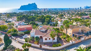 A coastal residential area with houses, palm trees, and a mountain in the background.
