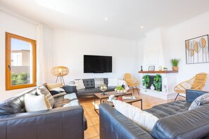 A modern living room with a sectional sofa, a flat-screen TV, and a fireplace.