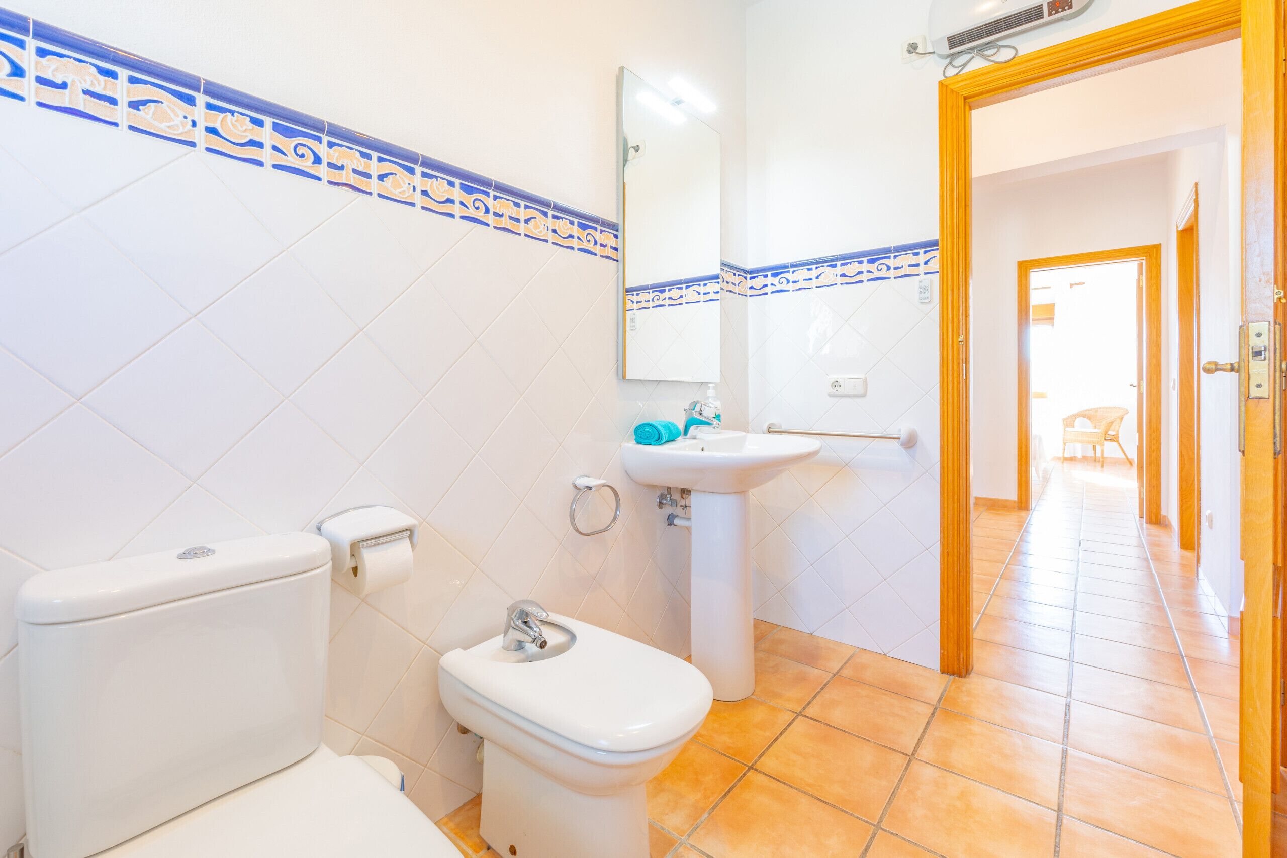 A bathroom with a toilet, bidet, sink, and mirror.