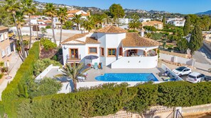 A two-story house with a swimming pool, surrounded by palm trees and other greenery. - Villa Altamira - Plus (Calpe)