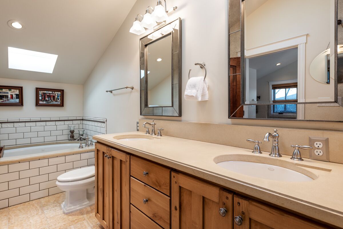 A modern bathroom with a double sink vanity, a large mirror, and a bathtub.