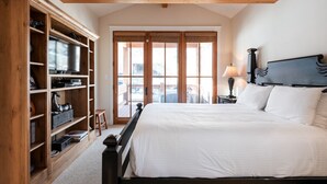 A bedroom with a large bed, wooden shelving unit, and a view through a sliding door. - Townhome Near Main St | Skiing | Hot Tub (Park City)