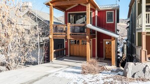 A two-story wooden cabin with a balcony, a garage, and a snow-covered driveway. - Townhome Near Main St | Skiing | Hot Tub (Park City)