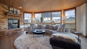 A spacious living room with a fireplace, large windows, and a cozy seating area.