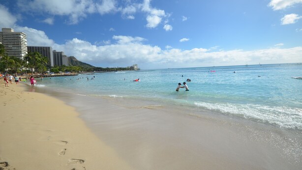 A beach with clear blue water, people swimming, and buildings in the background. - Sea Shore 41 Private Studio in Waikiki, 1 Block to Beach (Honolulu)