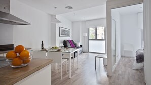 A modern kitchen with a dining area, a sofa, and a large window. - Blanca 1 - Habitat Apartments (Barcelona)