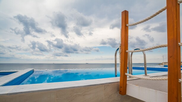 An infinity pool with a view of the sea and cloudy sky.