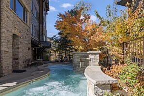 Relax in a serene hot tub surrounded by a traditional stone building and lush foliage.