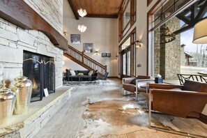 Experience the warmth of a cozy gathering space with a large stone fireplace, comfortable seating, and polished stone floors.