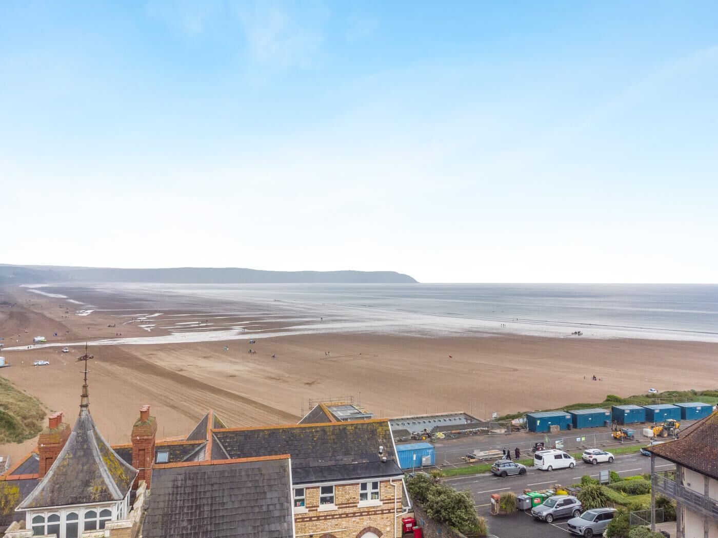 Une ville côtière avec une plage, des bâtiments et des voitures garées.