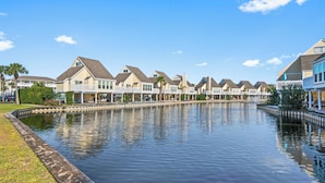 A waterfront property with multiple houses, a canal, and a grassy area. - Beachfront 2BR Free Beach Service Balcony Views (Destin)