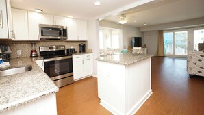A modern kitchen with white cabinetry, stainless steel appliances, and a granite countertop. - Beachfront 2BR Free Beach Service Balcony Views (Destin)