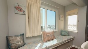 A room with a bench seat, two windows, and a view of the outside. - Beachfront 2BR Free Beach Service Balcony Views (Destin)