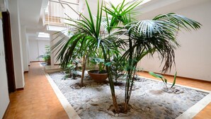 Ein geräumiger Innenhof mit einem zentralen Gartenbereich, der verschiedene Topfpflanzen und einen mit Kieselsteinen belegten Boden zeigt.