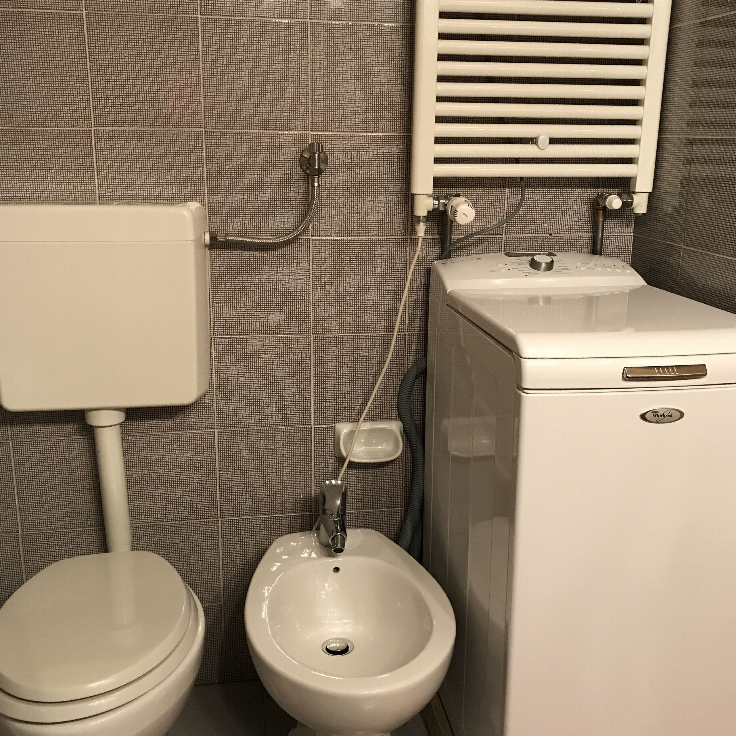 Een badkamer met toilet, bidet en wastafel.