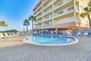 Un hotel con piscina, lettini e palme.
