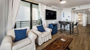 Un soggiorno moderno con due divani, un tavolino, una televisione e un'area pranzo con sedie e un tavolo.