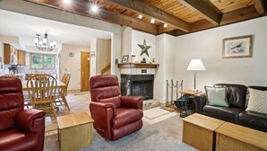 Un salón espacioso con chimenea, sillones de cuero, un sofá y una zona de comedor con muebles de madera.