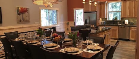 Un comedor con una gran mesa de madera dispuesta para una comida, rodeada de sillas.
