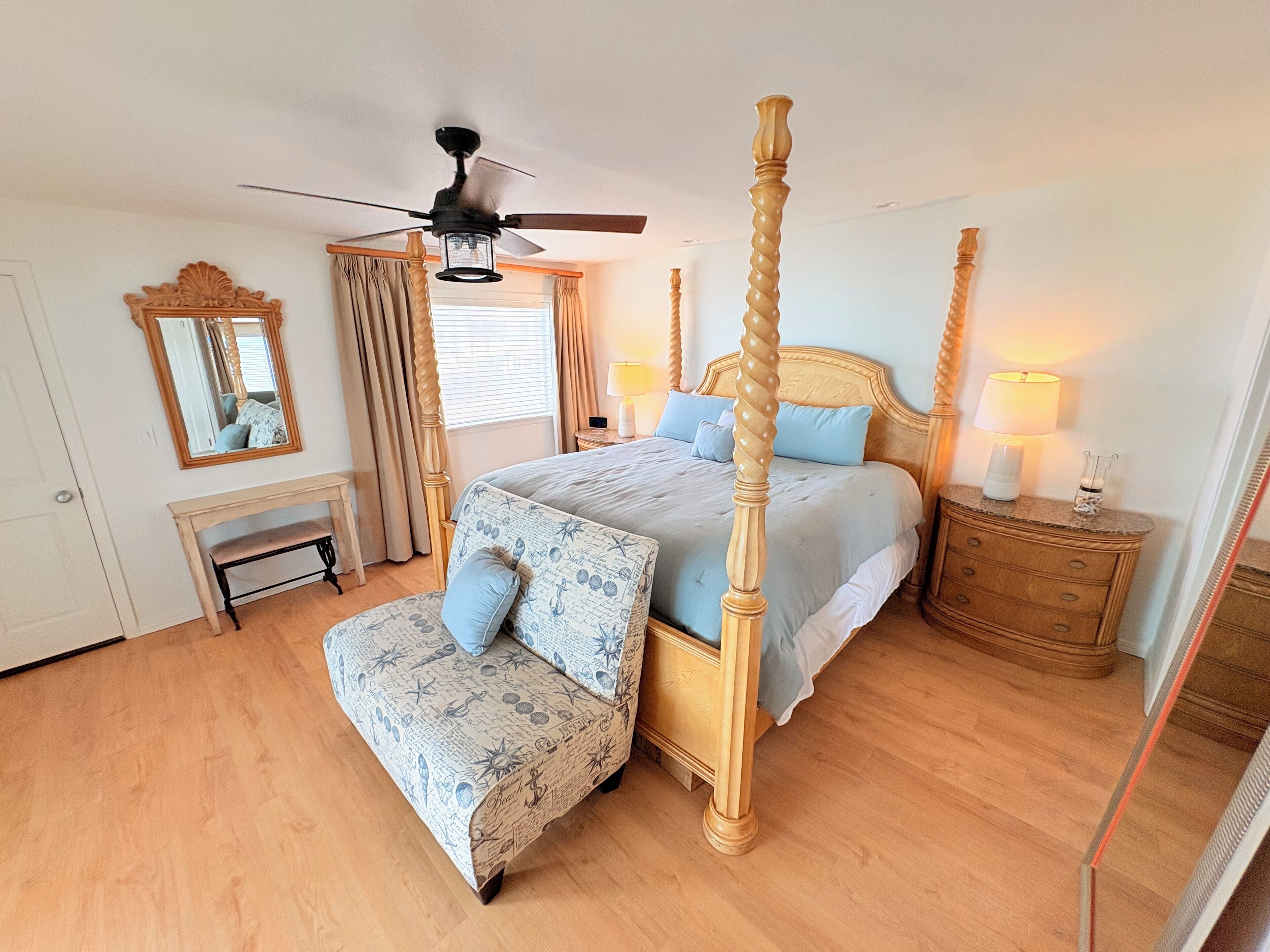 A four-poster bed with a canopy, a bench, a bedside table, and a mirror.
